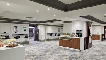 A spacious hotel lobby with a bar area, seating arrangements, and a reception desk.