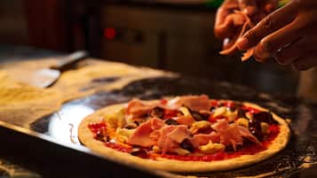 A pizza being prepared with toppings on a wooden surface.