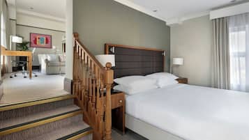 A hotel room with a bed, a desk, a chair, and a staircase.
