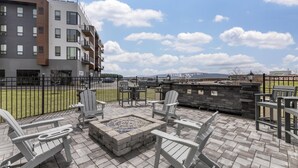 Une terrasse extérieure avec des fauteuils Adirondack, un foyer et un mur en pierre.