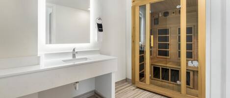 A bathroom with a white sink, mirror, and wooden cabinet with glass doors.