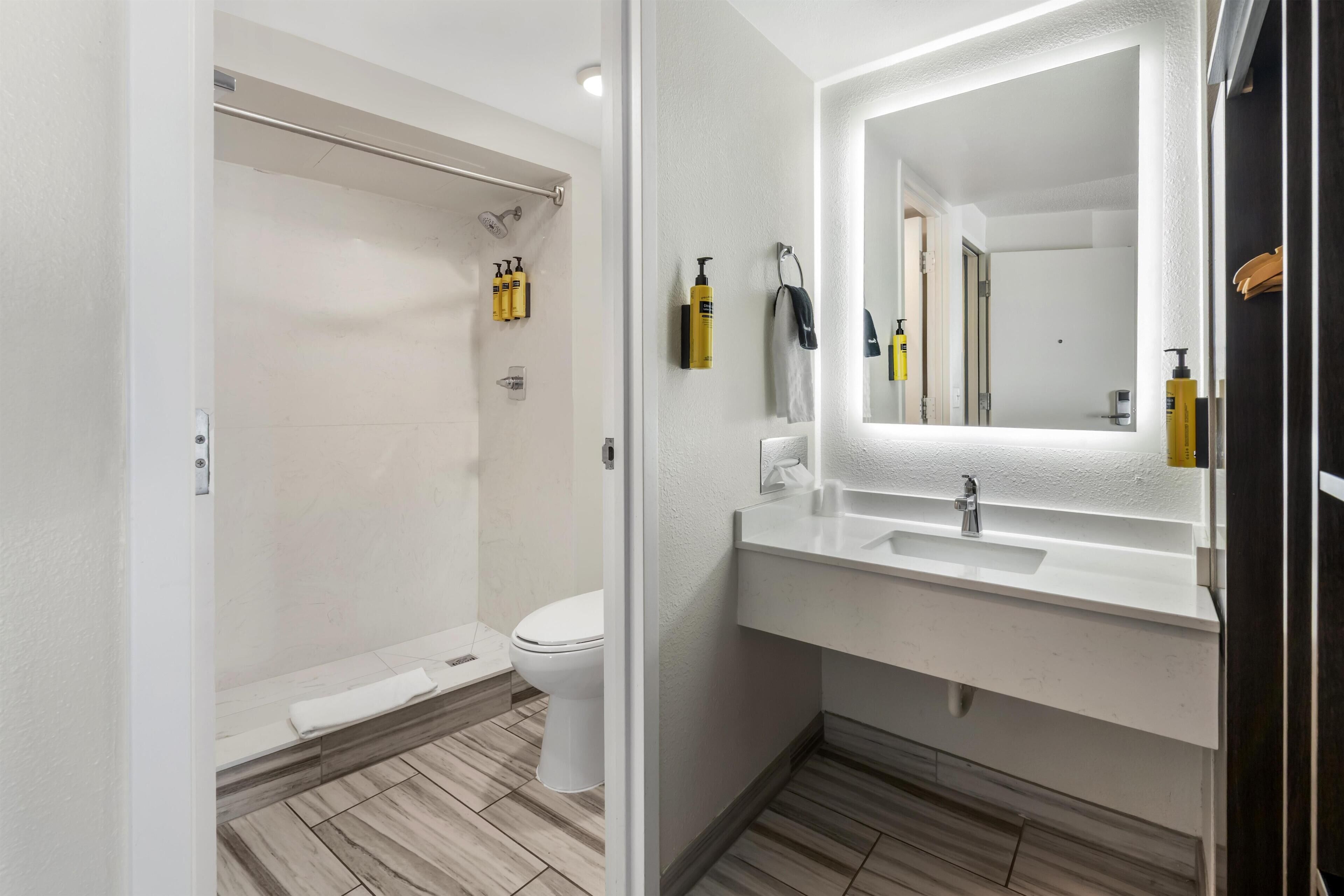 Een moderne badkamer met douche, toilet en wastafel met spiegel.