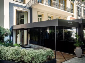 A hotel entrance with a covered outdoor area, a reception desk, and a potted plant. - Hôtel Le Soleia by Inwood Hotels (Nice)