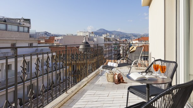 A balcony with a table, two chairs, a pair of glasses, and two glasses of a beverage. - HĂ´tel Le Soleia by Inwood Hotels (Nice)