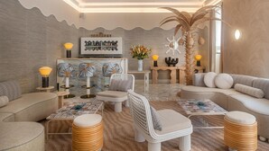 A modern living room with a bar area, comfortable seating, and a decorative palm tree. - HĂ´tel Le Soleia by Inwood Hotels (Nice)