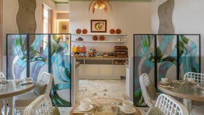 A dining area with a glass table, white chairs, and a decorative wall with leaf patterns. - HĂ´tel Le Soleia by Inwood Hotels (Nice)