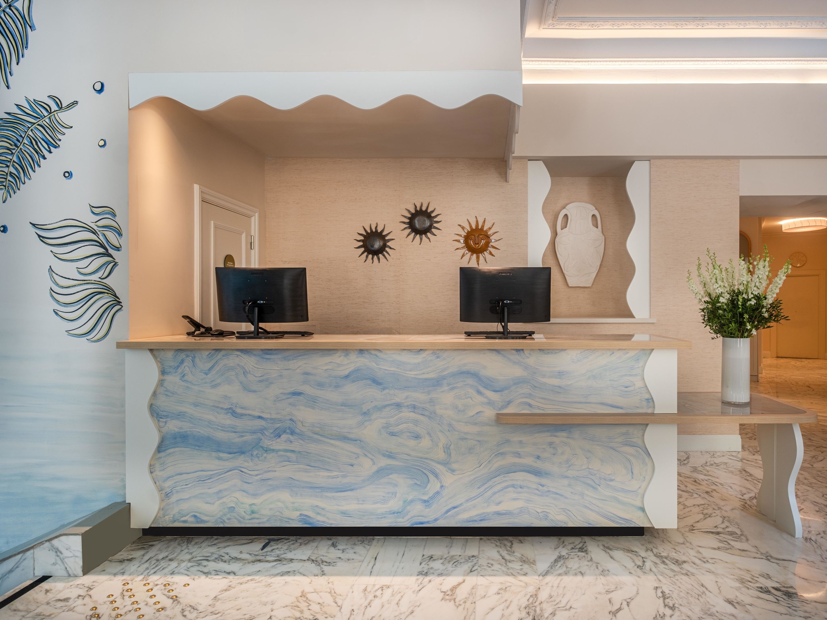Una reception con due monitor, un vaso di fiori e decorazioni a parete.