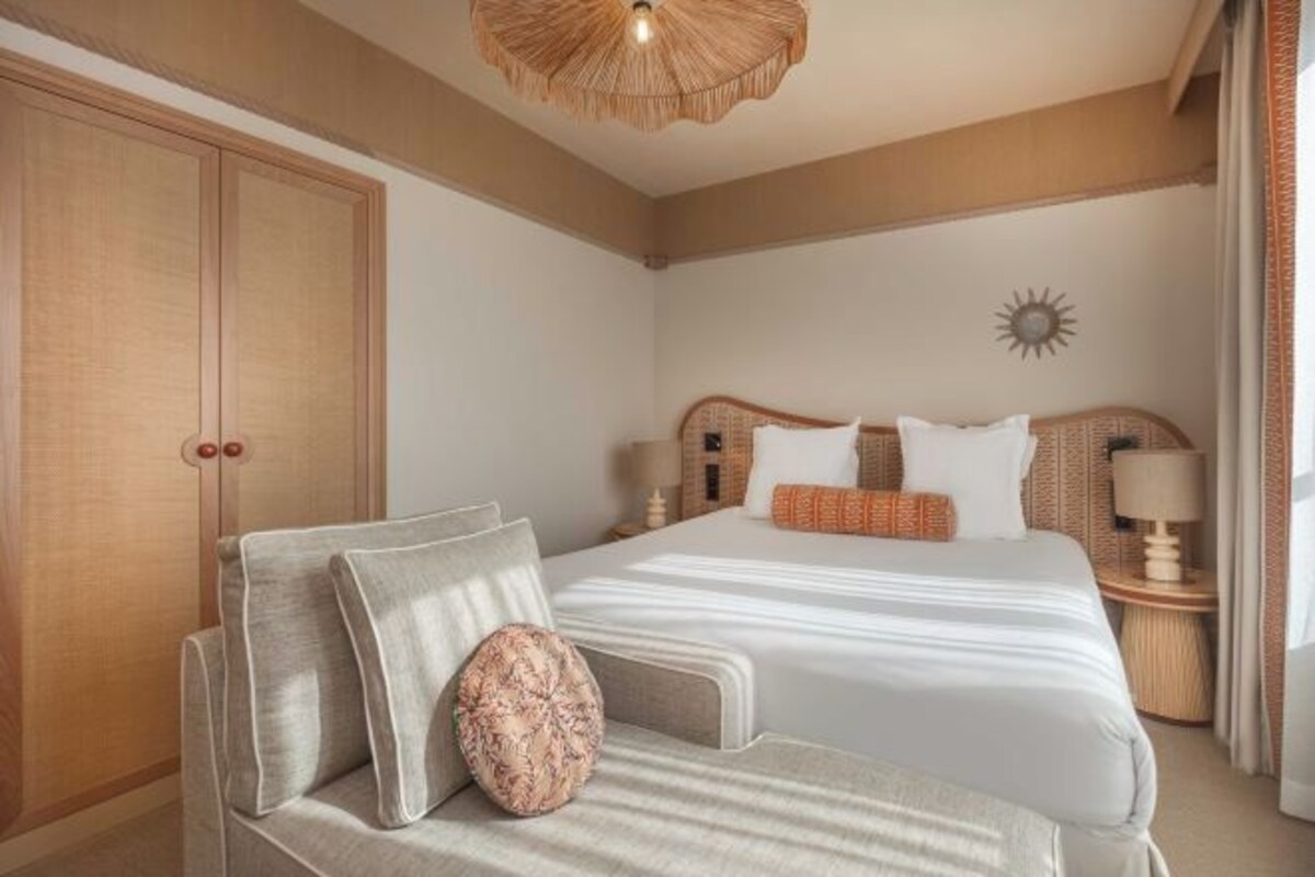 Habitación de hotel con cama, sofá, armario y un adorno de sol en la pared.
