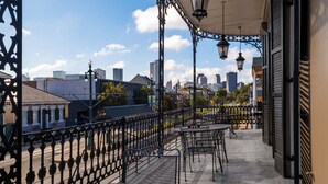 A balcony with wrought iron railings, tables, and chairs, overlooking a cityscape with buildings and a clear sky. - New Orleans Courtyard Hotel and Suites by the French Quarter (New Orleans)