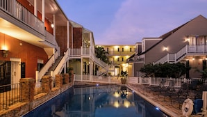 A pool area with a clear view of the pool, surrounding buildings, and a lifeguard chair. - New Orleans Courtyard Hotel and Suites by the French Quarter (New Orleans)