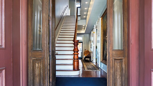 A grand staircase with a wooden handrail leading to an upper floor. - New Orleans Courtyard Hotel and Suites by the French Quarter (New Orleans)