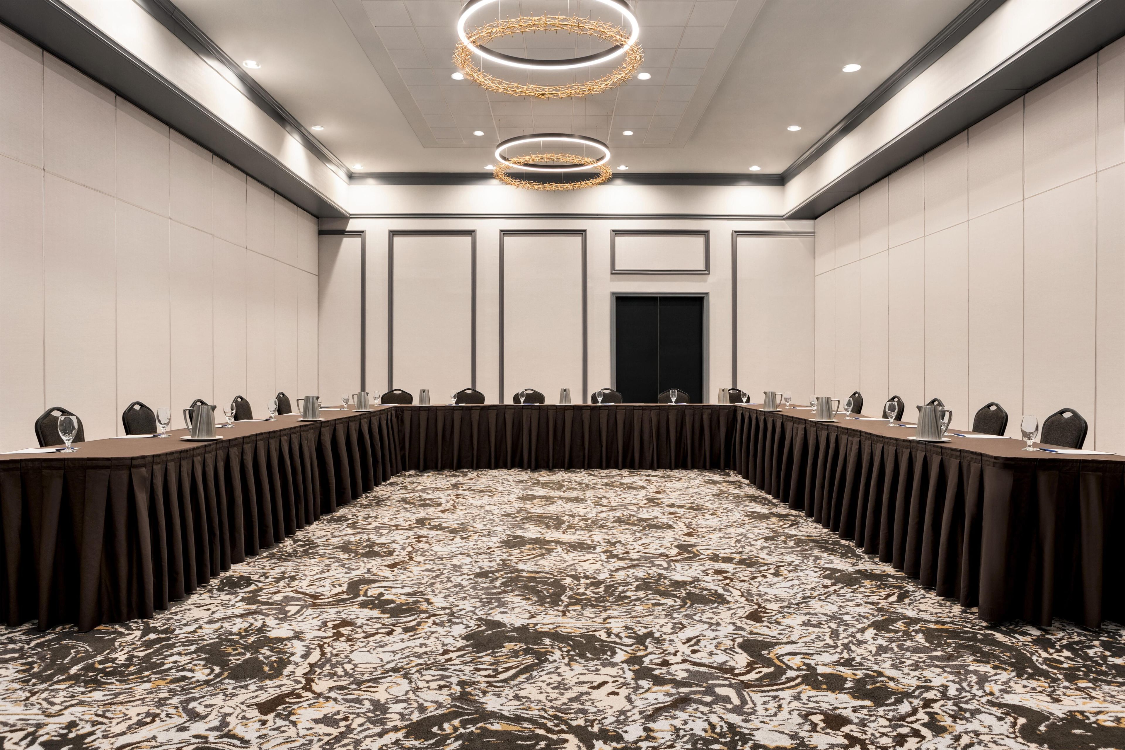 A conference room with a long table, chairs, and a patterned carpet.