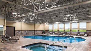 An indoor swimming pool with a hot tub, lounge chairs, and a view of the outdoors. - DoubleTree by Hilton Pointe Claire Montreal Airport West (Pointe Claire)