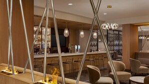 Een bar met een open haard, zitplaatsen en een toog vol flessen.