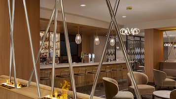A bar area with a fire feature, seating, and a bar counter with bottles.