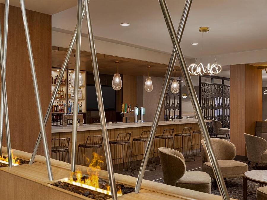 A bar area with a fire feature, seating, and a bar counter with bottles.