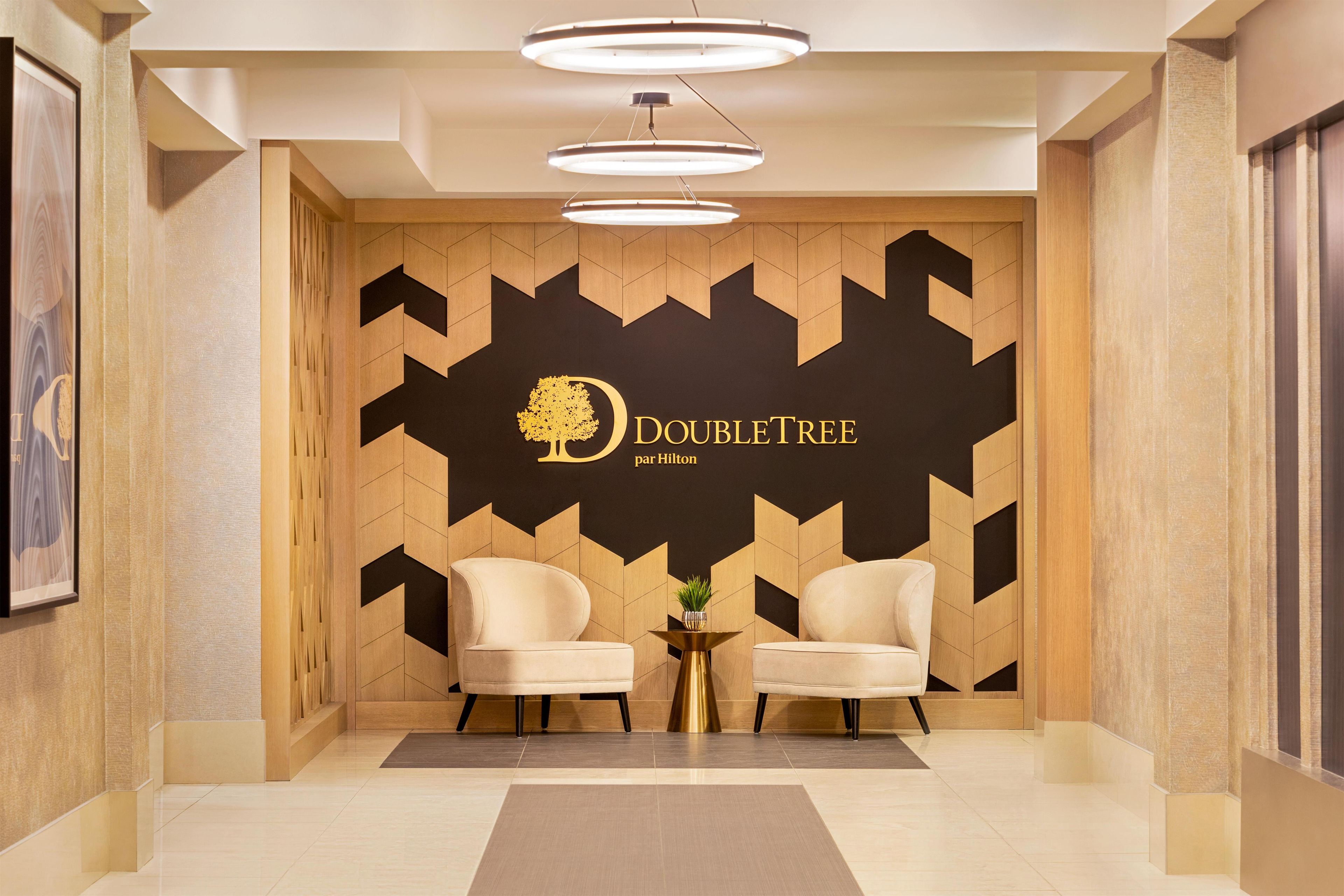 A reception area with two sofas, a wall-mounted logo, and a modern light fixture.