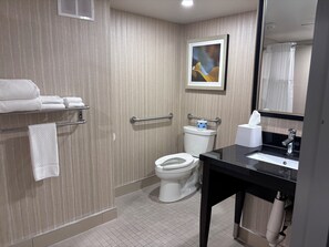 Een badkamer met toilet, wastafel, handdoekrek en een foto in een lijst aan de muur.