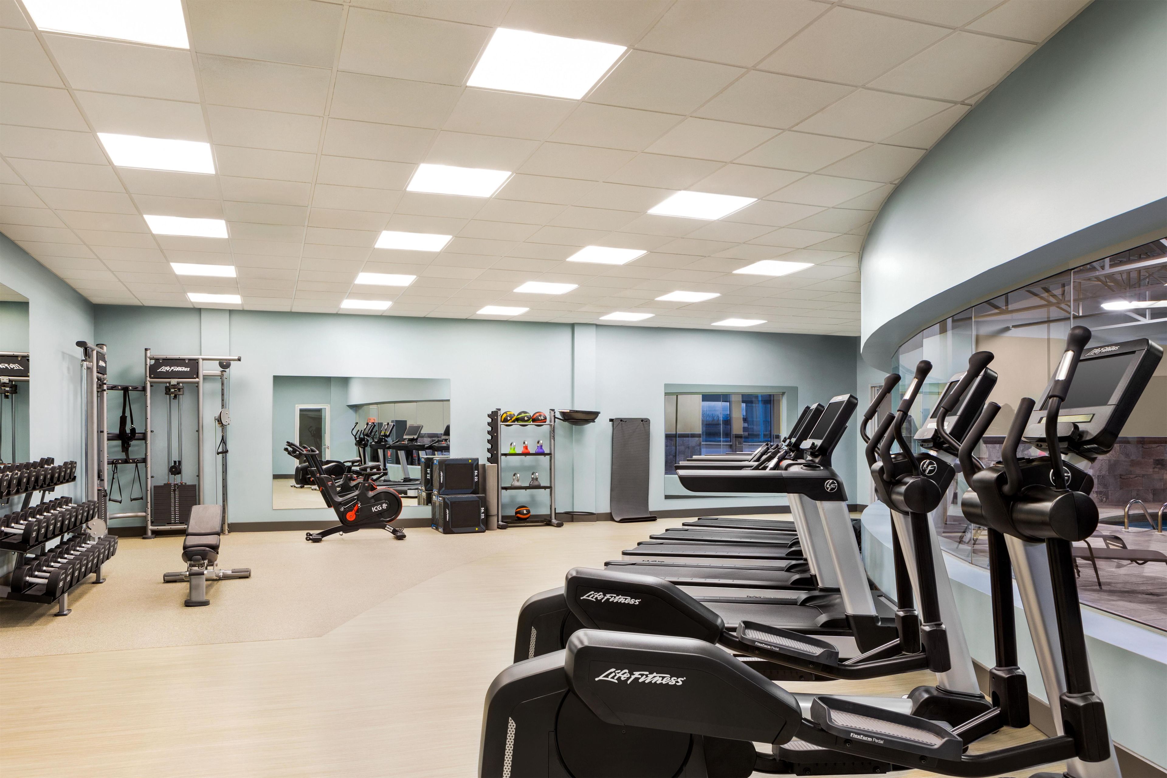 Uma academia com esteiras, halteres e aparelhos de musculação.