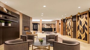 A modern lobby with a reception desk, seating area, and decorative wall panels. - DoubleTree by Hilton Pointe Claire Montreal Airport West (Pointe Claire)