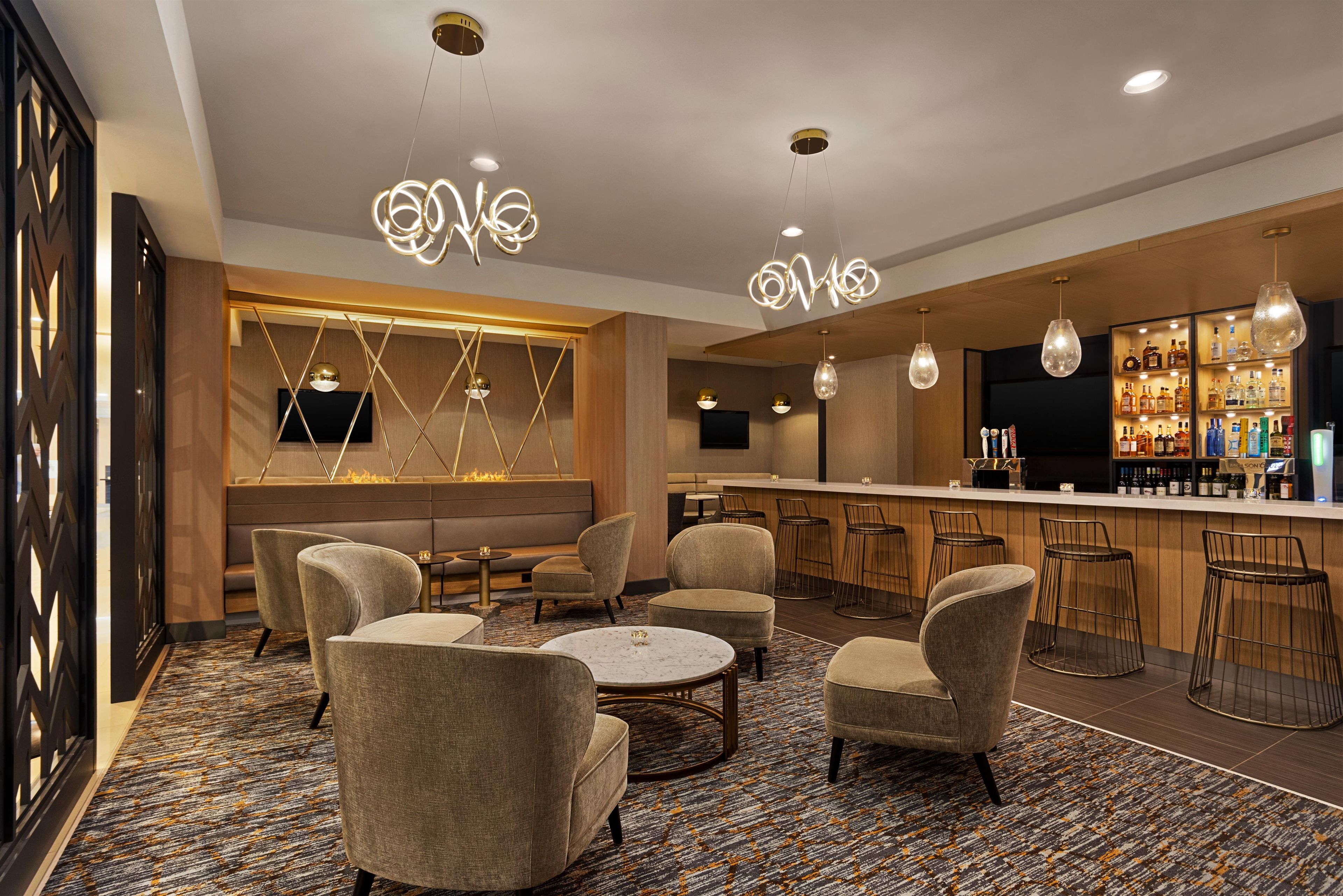 A bar area with seating, a bar counter, and overhead lighting.
