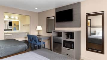 A hotel room with two beds, a desk, a chair, a TV, a mirror, and a coffee machine.