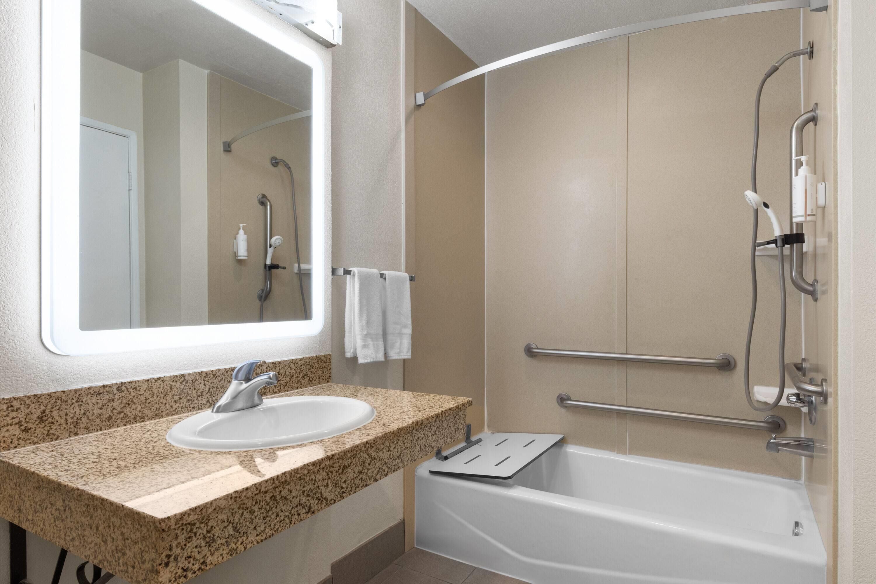 A bathroom with a sink, mirror, and bathtub.