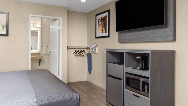 A hotel room with a bed, a TV mounted on the wall, a minibar, and a microwave. - Travelodge by Wyndham Banning CA Near Casino/Outlet Mall (Banning)