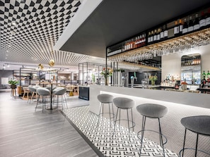 Un área de bar moderna con techo a cuadros, taburetes y suelo estampado.