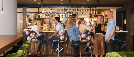 A bar area with a counter, stools, and a variety of bottles and glasses.