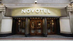 Ein Hotel Eingang mit einem markanten 'NOVOTEL'-Schild, großen Glasüren und klassischer Architektur.