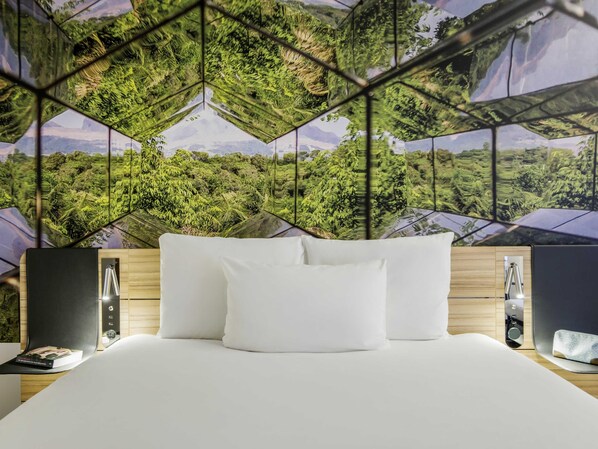 A modern hotel room with a large bed, white pillows, and a geometric-patterned wall mural. - Novotel Den Haag City Centre (The Hague)