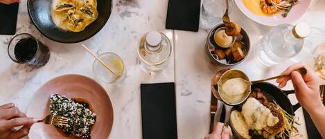 A dining table with various dishes, utensils, and glasses.