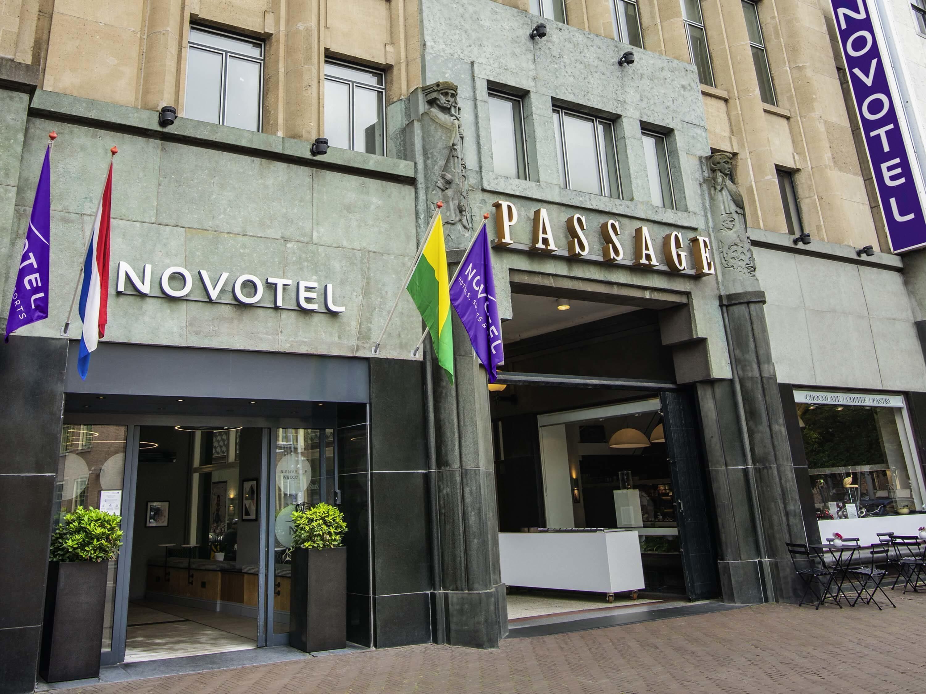 A hotel with a 'NOVOTEL' sign, a 'PASSAGE' entrance, and a 'CHOCOLATE COFFEE PASTRY' shop.