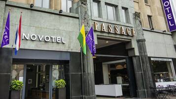 A hotel with a 'NOVOTEL' sign, a 'PASSAGE' entrance, and a 'CHOCOLATE COFFEE PASTRY' shop.