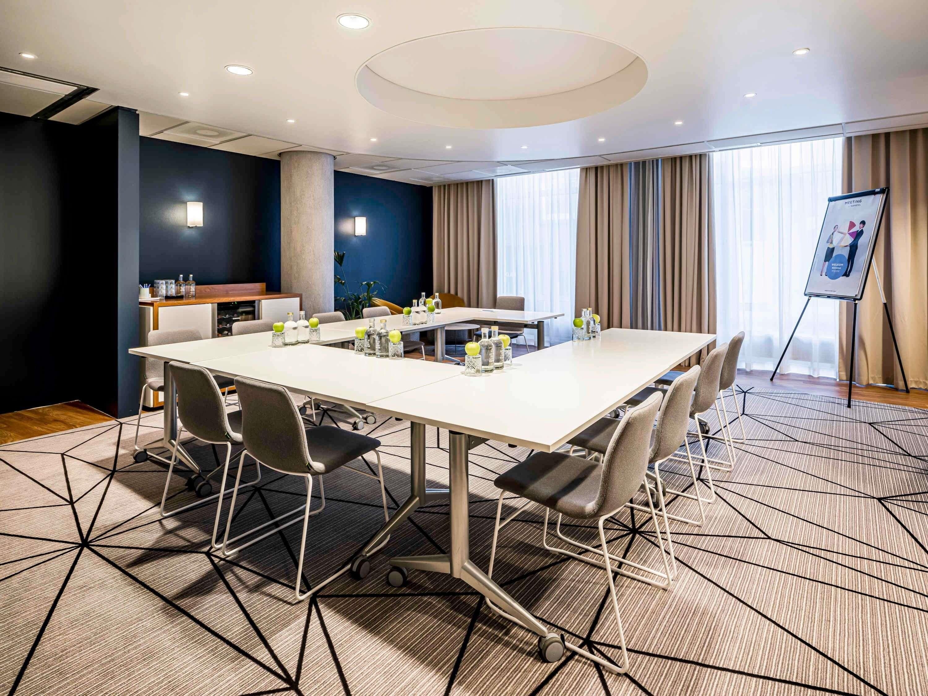 A conference room with a large table, chairs, a projector screen, and a small kitchenette.