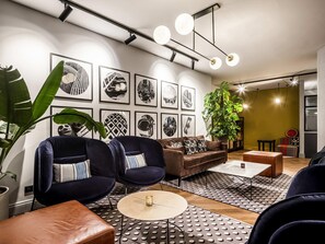 Ein modernes Wohnzimmer mit einer Couch, Sesseln, einem Couchtisch und einer großen Pflanze.