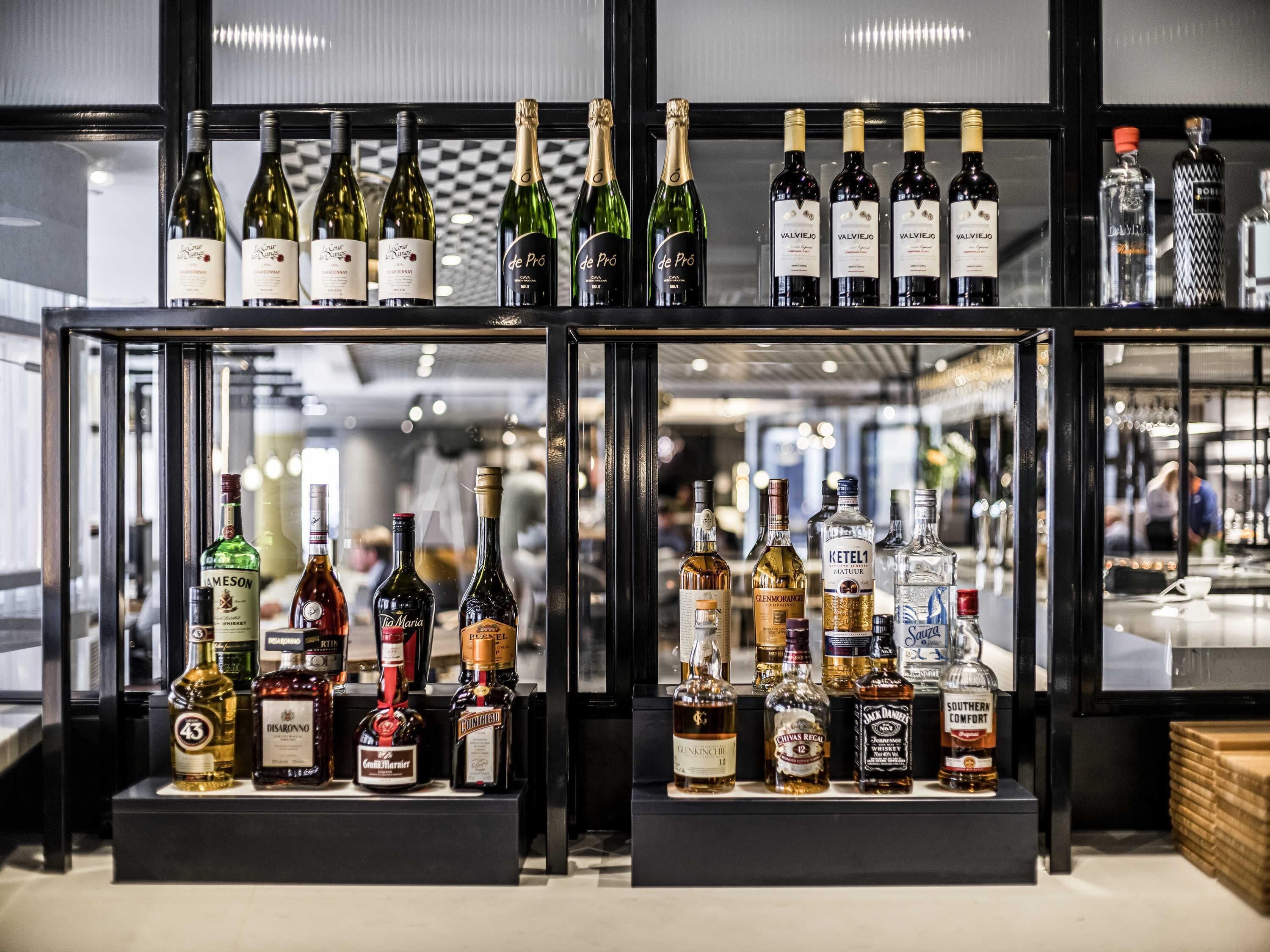 A bar area with various bottles of alcohol, including wine and spirits, displayed on shelves.