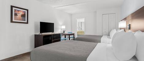 A hotel room with a large bed, a desk with a computer, a TV, and a framed picture on the wall.