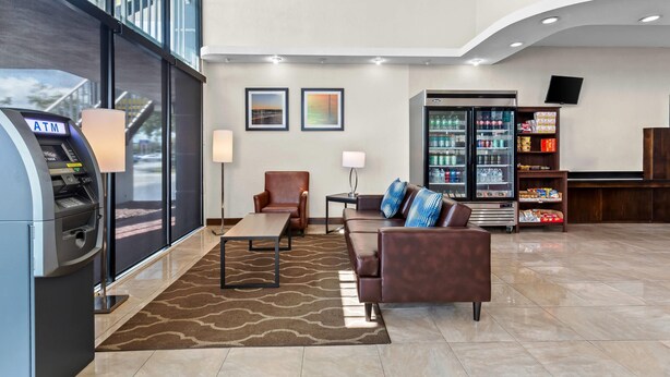 Un hall con zona de estar, cajero automático, nevera con bebidas y televisor montado en la pared.