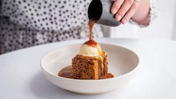 Postre amb una bola de gelat a sobre, regat amb salsa.