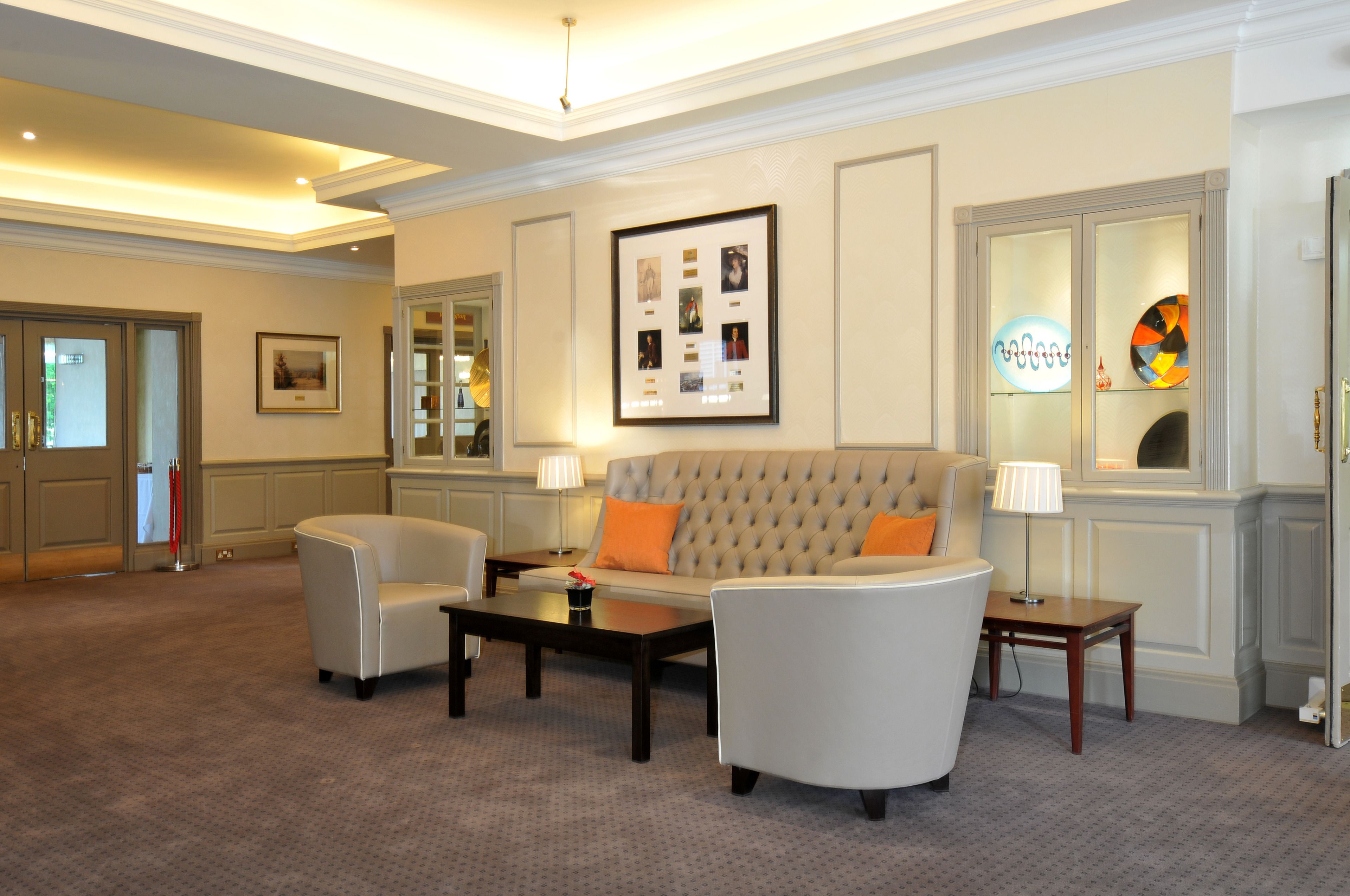 A well-lit living room with a sofa, two armchairs, a coffee table, and a framed photo on the wall.