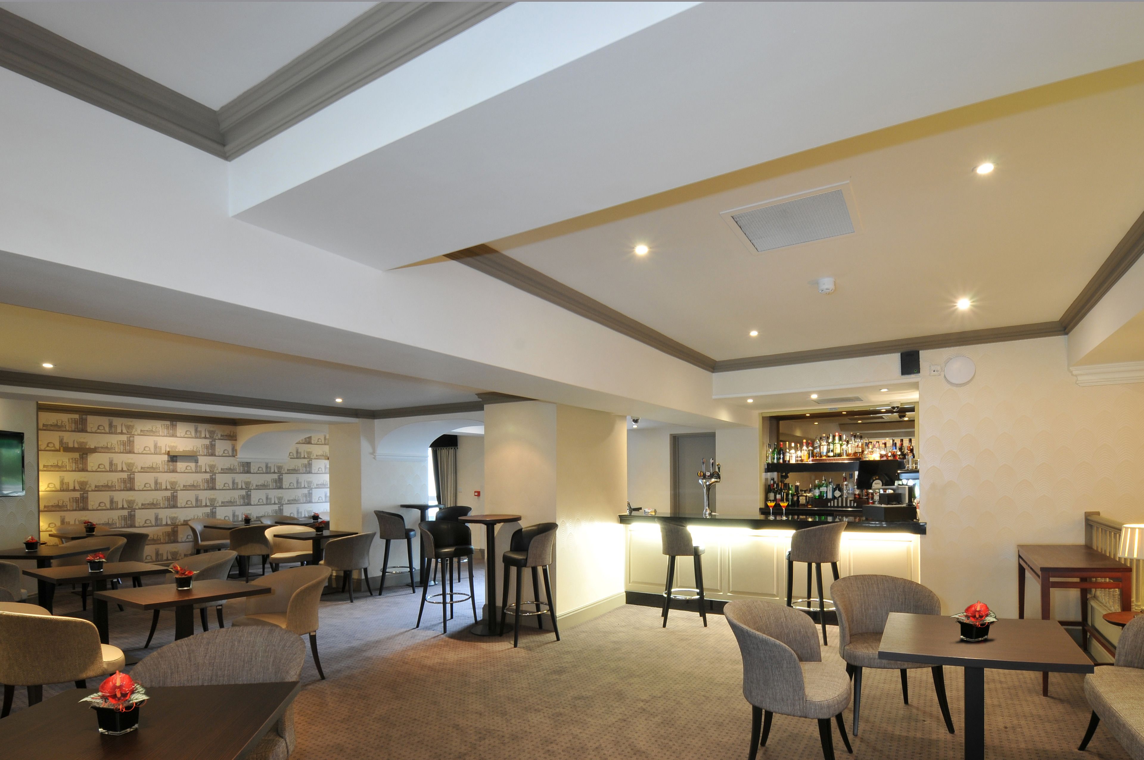 A hotel lobby with multiple seating areas, a bar, and a patterned wall.