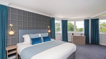 A hotel room with a large bed, a nightstand, a dresser, and a window with curtains.
