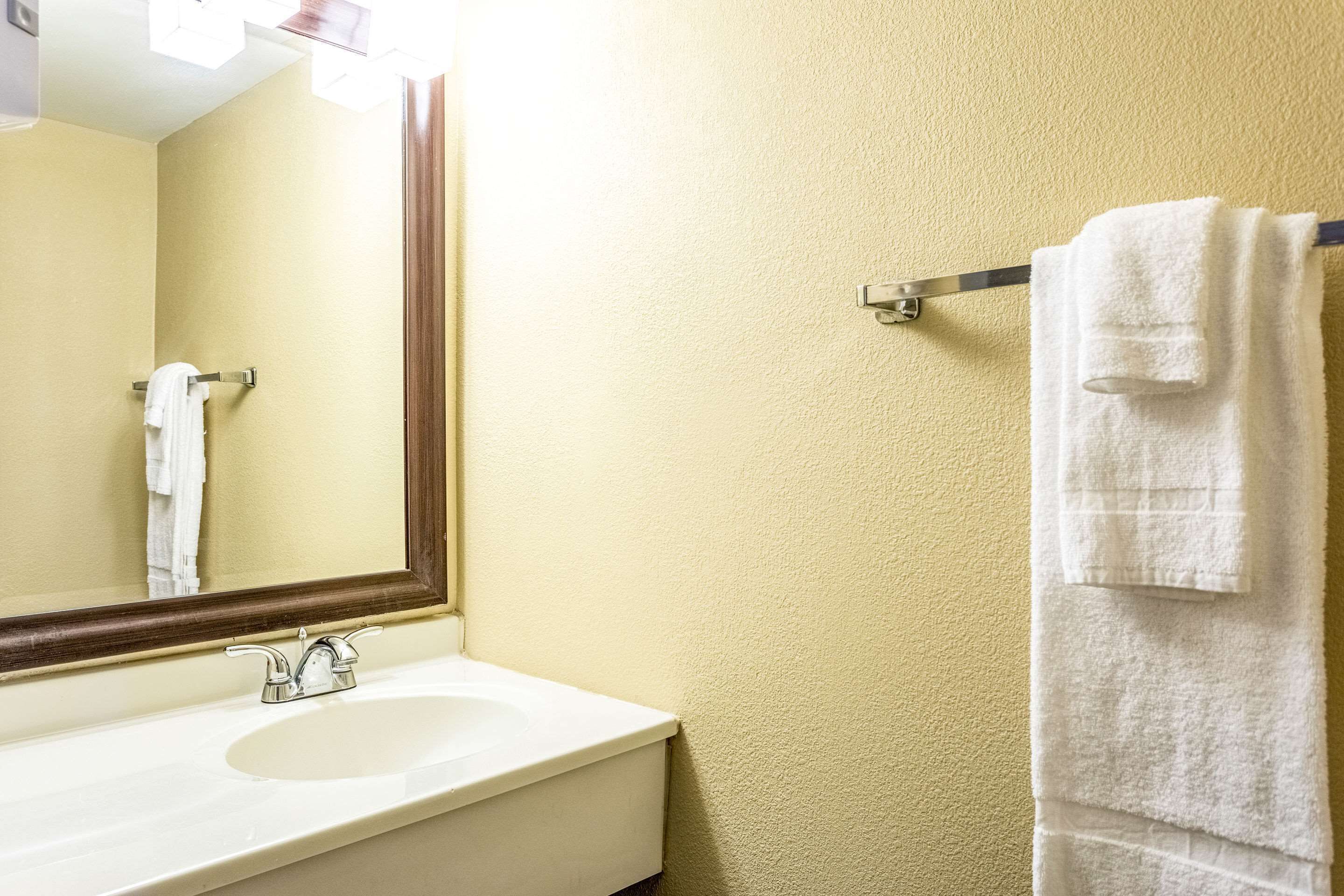 A bathroom with a white sink, a mirror, and a towel rack with a folded towel.