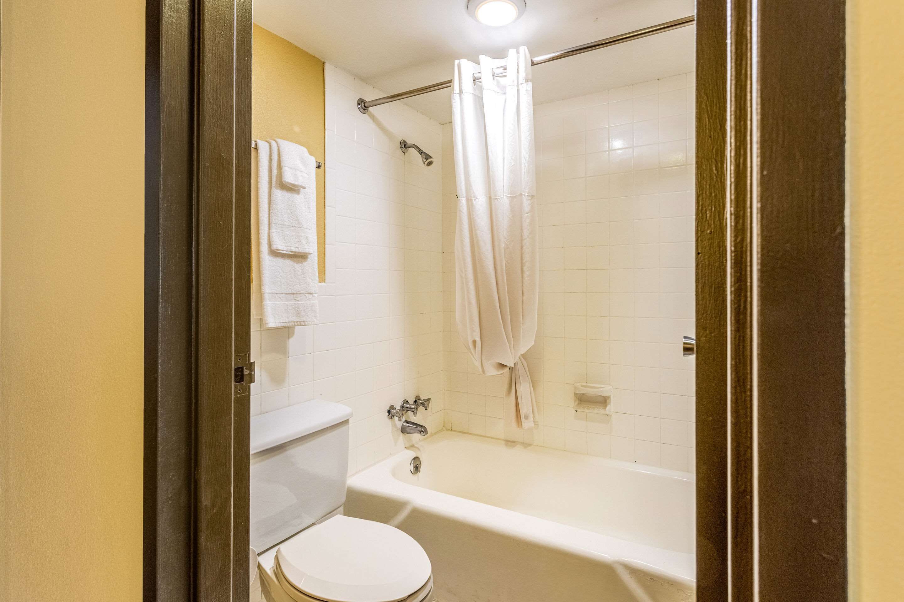 A bathroom with a toilet, bathtub, and shower curtain.