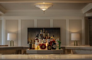 A bar area with a variety of liquor bottles and two lamps on either side.
