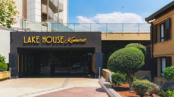 The exterior of Lake House Kinneret, featuring a modern facade, a gated entrance, and a landscaped garden area.