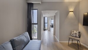 A modern living room with a grey sofa, a patterned armchair, and a large window with curtains. - Lake House Kinneret (Tiberias)
