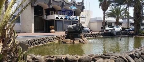 A hotel with a pool, palm trees, and a sign that reads "Tiberias Hot Springs".